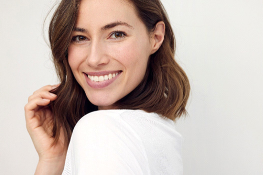 Woman in white shirt looking over shoulder smiling