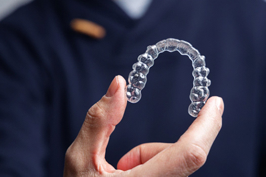Man in navy scrubs holding Invisalign tray