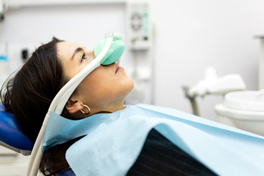 Profile view of woman in dental chair with green nitrous oxide mask over nose