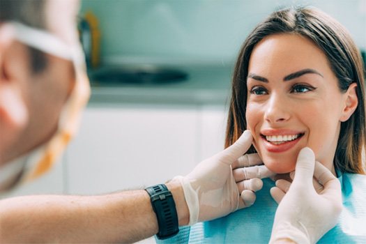 Dentist touching patient’s cheeks with gloved hands