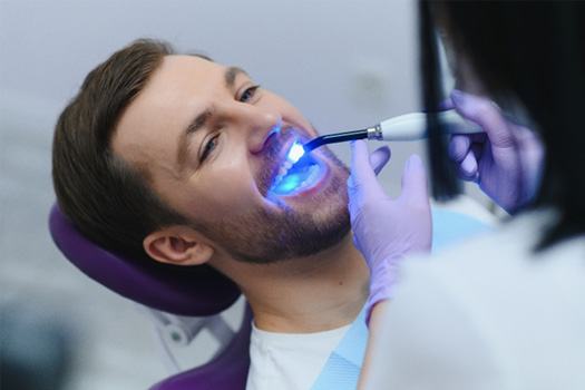 Dentist applying UV light to patient’s cavity filling
