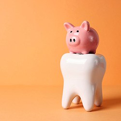 Pink piggy bank on top of large model tooth with orange background
