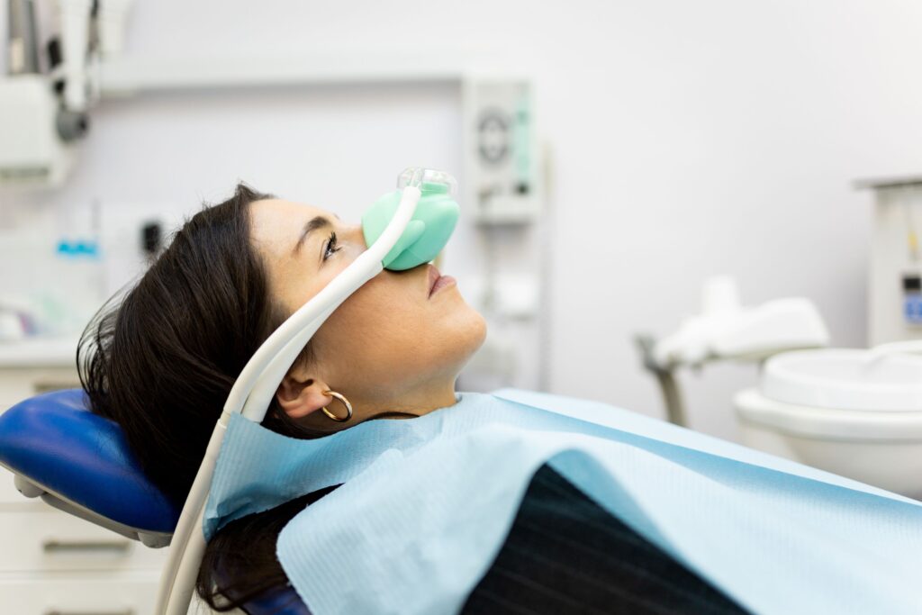 Profile view of woman in dental chair with green nitrous oxide mask over nose
